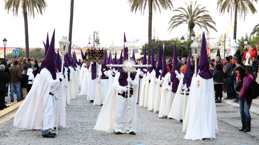 Nazarenos con túnicas blancas y capirotes morados en la Semana Santa de Ceuta.
