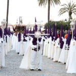 Nazarenos con túnicas blancas y capirotes morados en la Semana Santa de Ceuta.