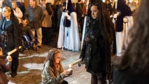 Procesión de Semana Santa en Granada contemplada desde la calle entre público y nazarenos.