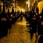 Nazarenos de la Cofradía del Calvario de Sevilla durante la Semana Santa, vestidos con túnicas oscuras.