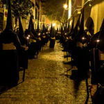 Nazarenos de la Cofradía del Calvario de Sevilla durante la Semana Santa, vestidos con túnicas oscuras.