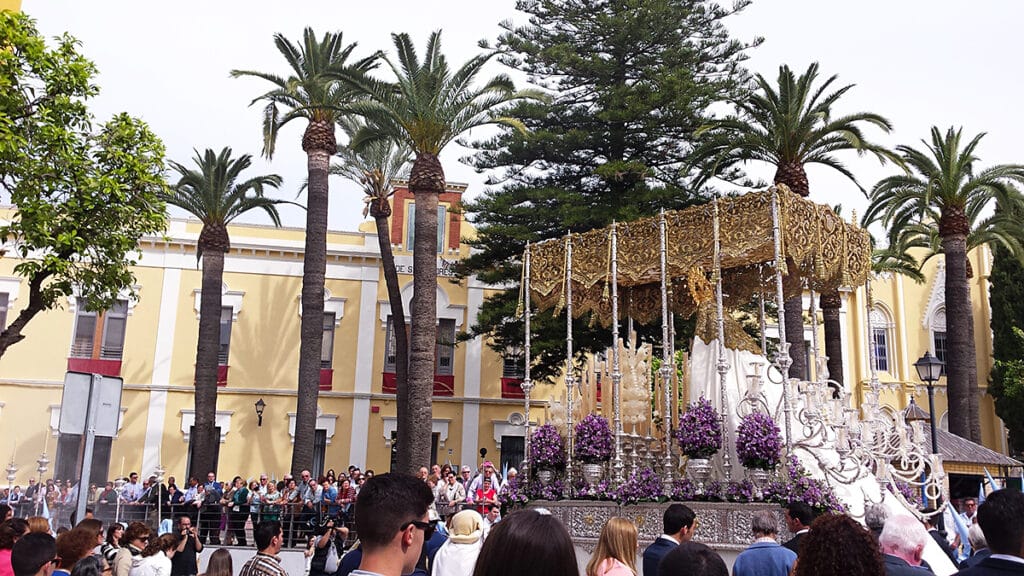 Procesión de Semana Santa con público a ambos lados de la calle en Lebrija.