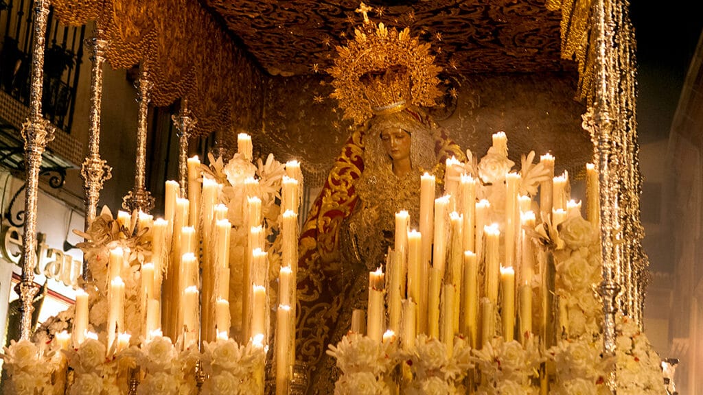 Procesión de Semana Santa recorriendo una calle de Granada durante la noche.