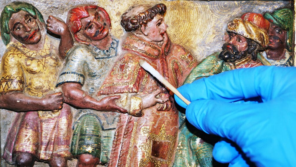 Conservador-restaurador realizando un tratamiento sobre una talla histórica de madera policromada.