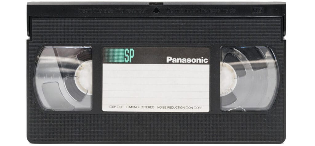 Casete VHS Panasonic en vista frontal, sobre fondo claro, con etiqueta central en blanco y bobinas visibles.