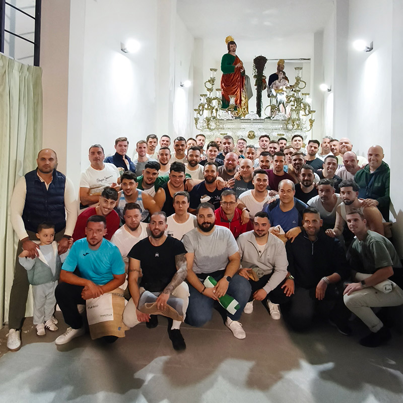Fotografía de grupo de los costaleros de Jesús de la Victoria en el interior de la Casa de Hermandad, con el misterio al fondo.
