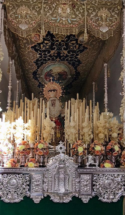 Detalle del paso de palio de Nuestra Señora del Valle con flores claras, candelería y elementos de orfebrería.
