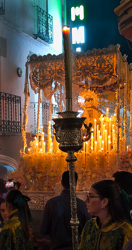 Paso de la Virgen del Valle iluminado entre fachadas cercanas, con público contemplando su recorrido nocturno.