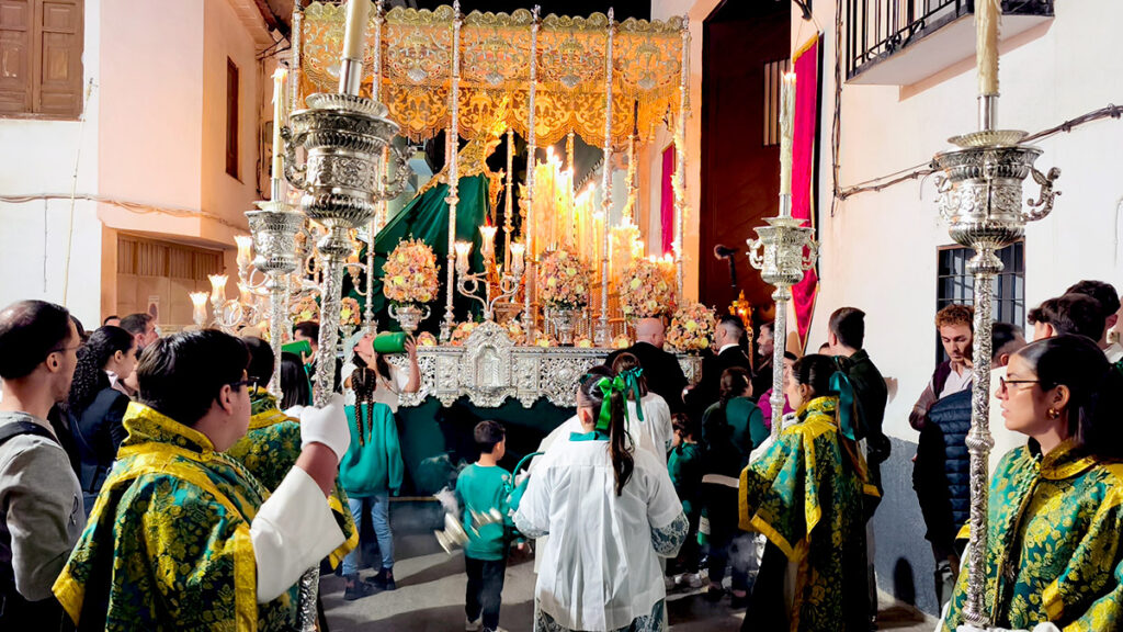 Integrantes del cortejo procesional junto al paso de palio de Nuestra Señora del Valle durante la noche.
