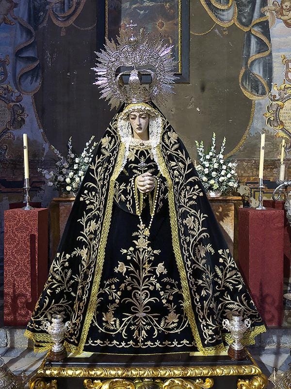 Nuestra Señora de la Soledad de Granada vestida de negro y bordados dorados, expuesta en altar de culto.