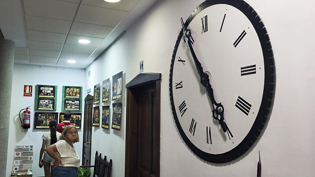 Reloj del Ayuntamiento de Padul junto a la exposición del XXV Aniversario de La Borriquilla
