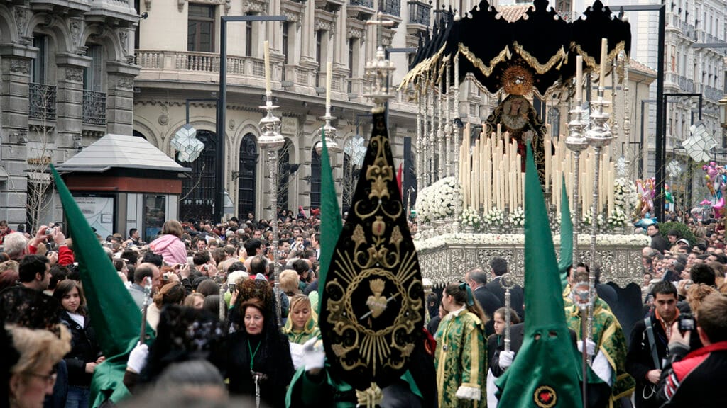 Procesión de Semana Santa recorriendo una calle de Granada ante el público.