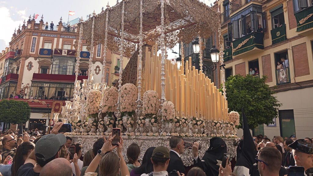 Paso de palio en la Semana Santa de Sevilla, rodeado por el público.