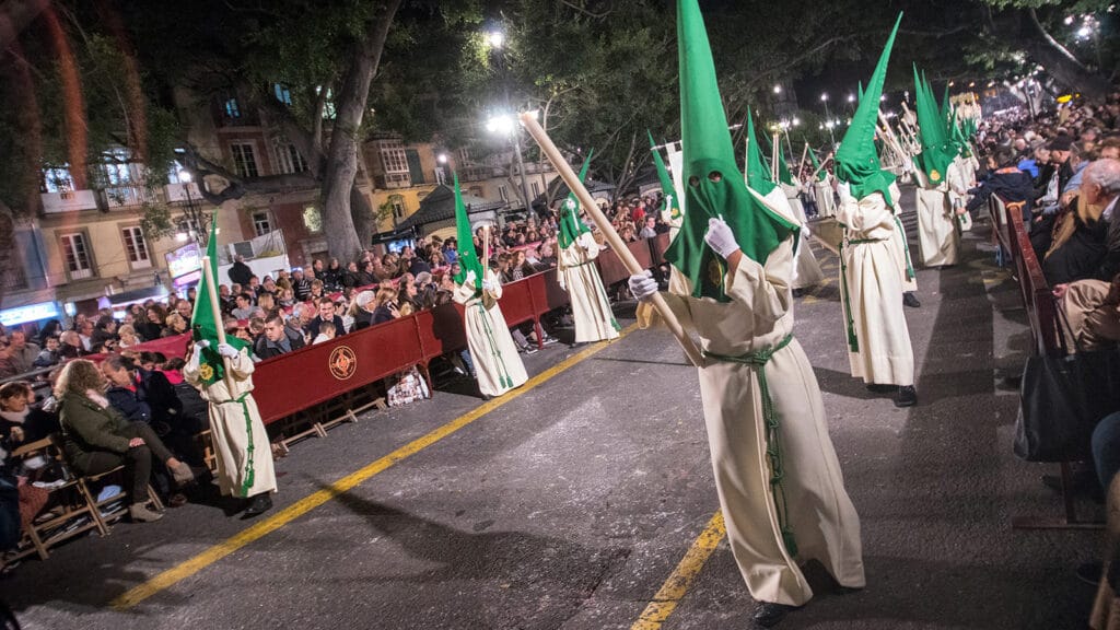 Nazarenos con capirotes verdes de la Hermandad de Nueva Esperanza durante la Semana Santa de Málaga.