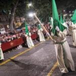 Nazarenos con capirotes verdes de la Hermandad de Nueva Esperanza durante la Semana Santa de Málaga.