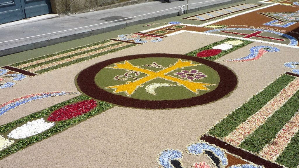 Alfombra floral elaborada para el Corpus Christi de Ponteareas, con diseños religiosos y ornamentales sobre la calle.