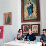La alcaldesa de Padul, Celia Villena, el hermano mayor de la Borriquilla, Andrés Rejón, y el párroco, Carlos José Fernández, sentados a una mesa presidiendo la presentación del XXV Aniversario en los Salones Parroquiales.