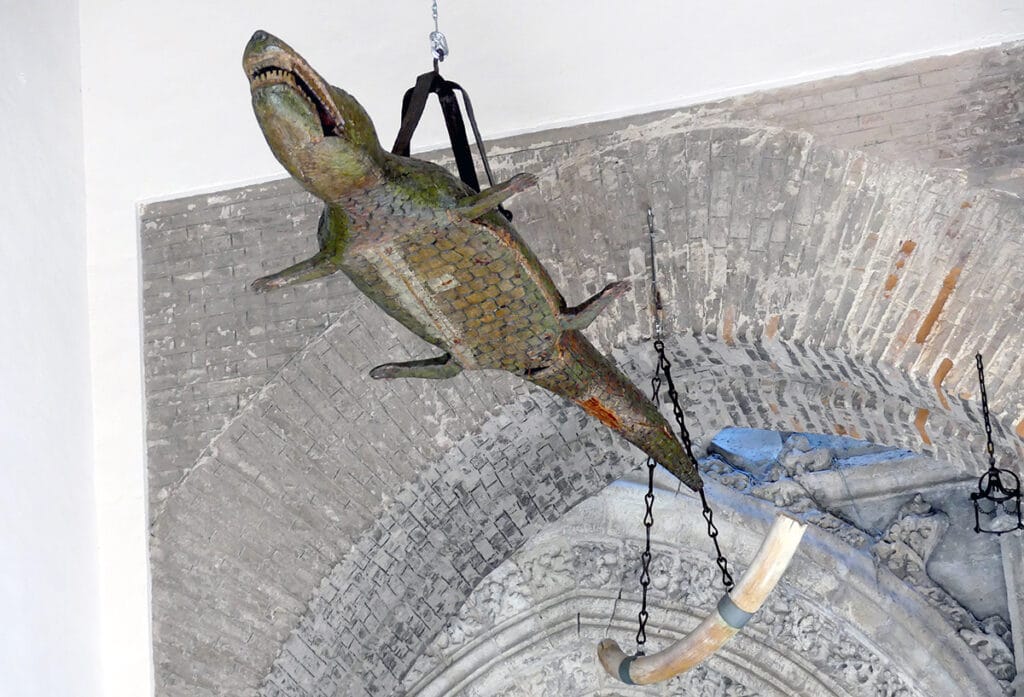 Cocodrilo disecado y colmillo expuestos en la Catedral de Sevilla, asociados a la tradición del “Lagarto”.