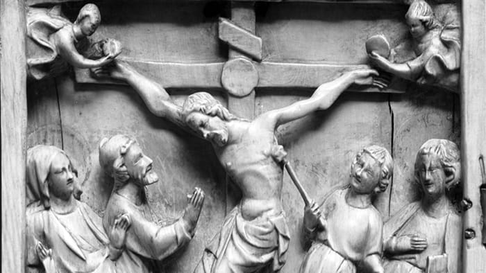 Relieve medieval con Crucifixión: figura que eleva una esponja hacia la cruz junto a otros personajes de la Pasión.