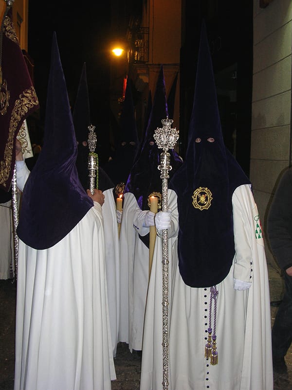 Nazarenos de una hermandad sevillana en procesión nocturna.