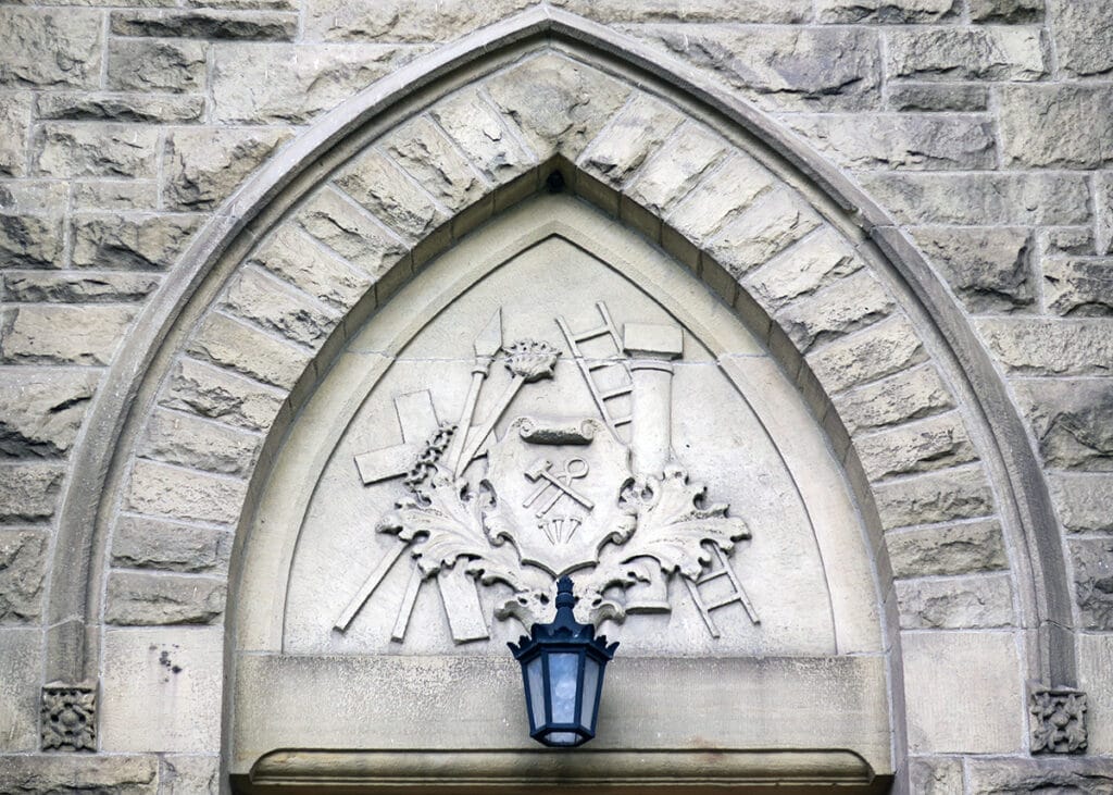 Relieve arquitectónico con instrumentos de la Pasión (Arma Christi) dispuestos como emblemas alrededor de la cruz.