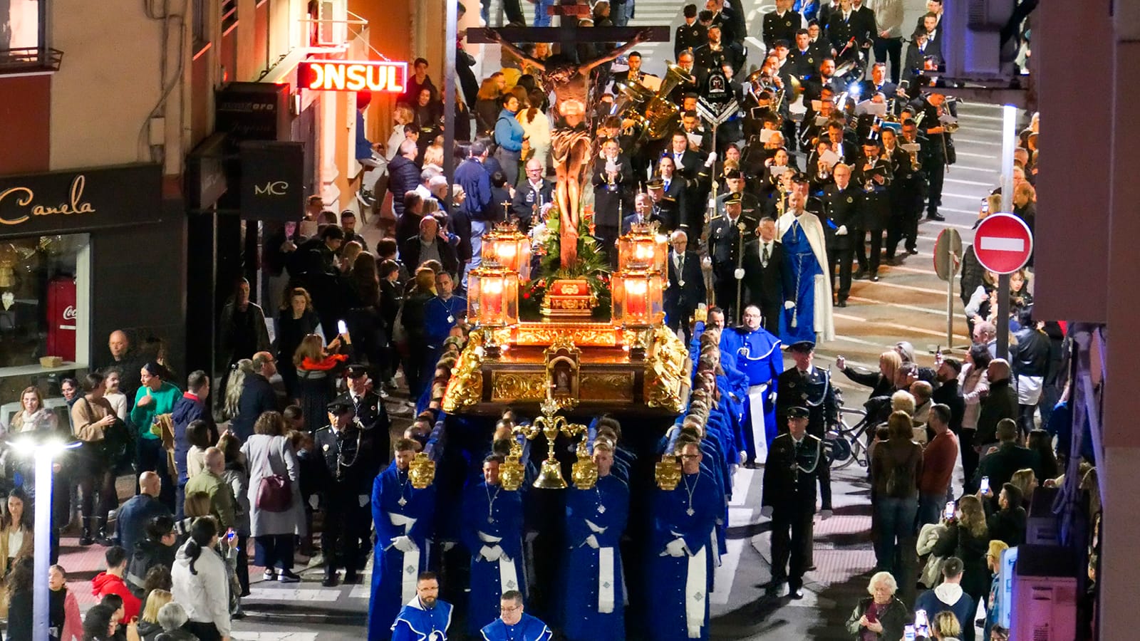 Procesión de Semana Santa en Alicante con nazarenos y paso en un encuadre amplio.