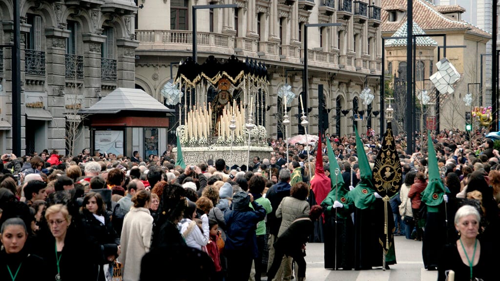 Procesión de Semana Santa en Granada avanzando por la calle con el paso rodeado de fieles. 