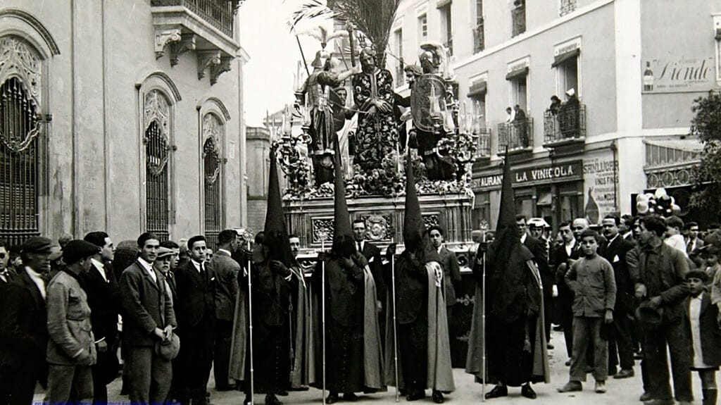 Escena histórica de la Semana Santa de Sevilla, hacia 1926, con público y cortejo ocupando el espacio urbano.