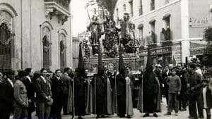 Escena histórica de la Semana Santa de Sevilla, hacia 1926, con público y cortejo ocupando el espacio urbano.