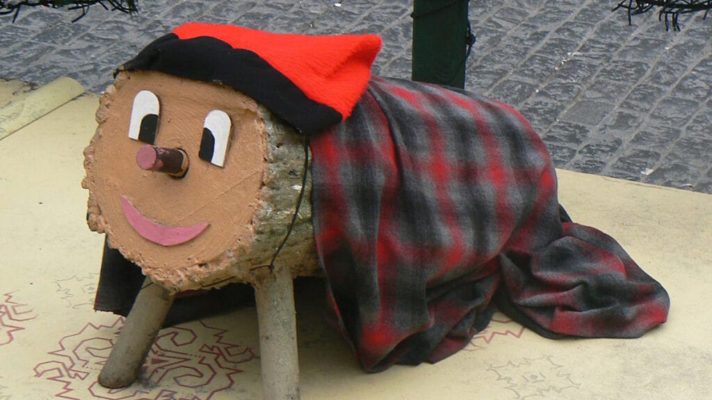 Tronco decorado como Tió de Nadal, con rasgos y elementos festivos.