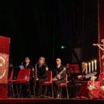 Antonio Carlos Maldonado en el atril, con la Banda San Sebastián y la decoración del escenario al fondo.