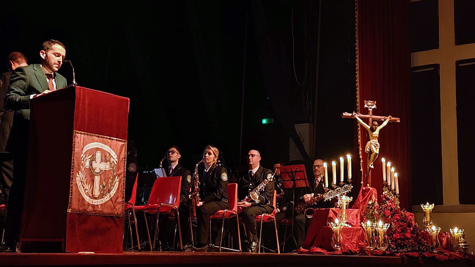 Antonio Carlos Maldonado en el atril, con la Banda San Sebastián y la decoración del escenario al fondo.