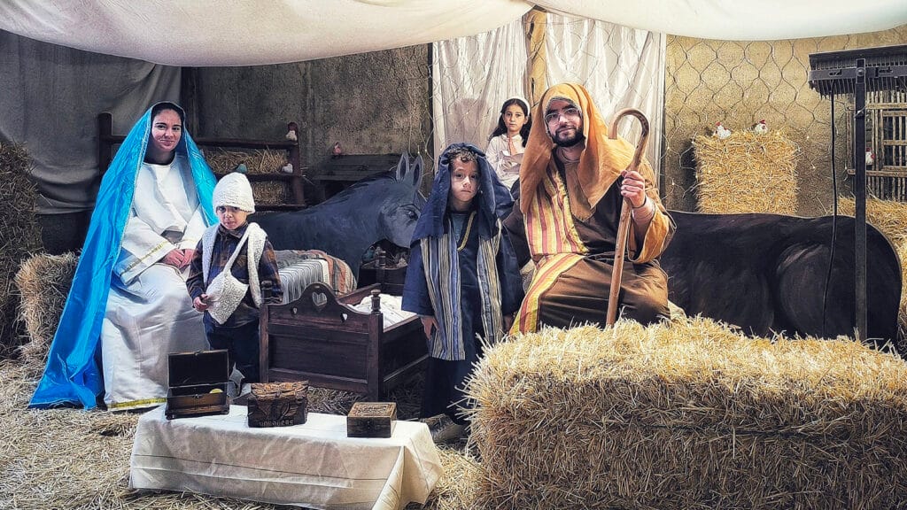 Escena del pesebre en interior, con figurantes caracterizados, paja y animales en la Casa Grande.