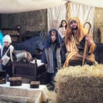 Escena del pesebre en interior, con figurantes caracterizados, paja y animales en la Casa Grande.