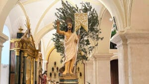 Vista del Señor Resucitado de Padul en el interior del templo, con estandarte, ramas de olivo y arcadas de la iglesia.