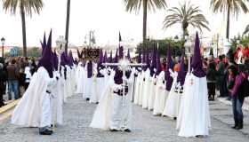 Nazarenos con túnicas blancas y capirotes morados en la Semana Santa de Ceuta.