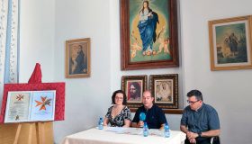 La alcaldesa de Padul, Celia Villena, el hermano mayor de la Borriquilla, Andrés Rejón, y el párroco, Carlos José Fernández, sentados a una mesa presidiendo la presentación del XXV Aniversario en los Salones Parroquiales.