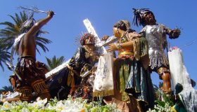 Jesús yacente en urna procesional, acompañado de flores, en la Semana Santa de Trapani.