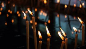 Velas votivas encendidas en un soporte metálico dentro de una iglesia.