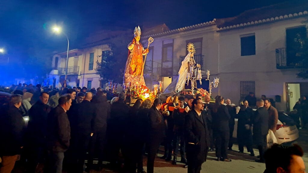 Procesión nocturna con San Blas y la Virgen del Carmen entre el gentío, iluminados por la candelería.