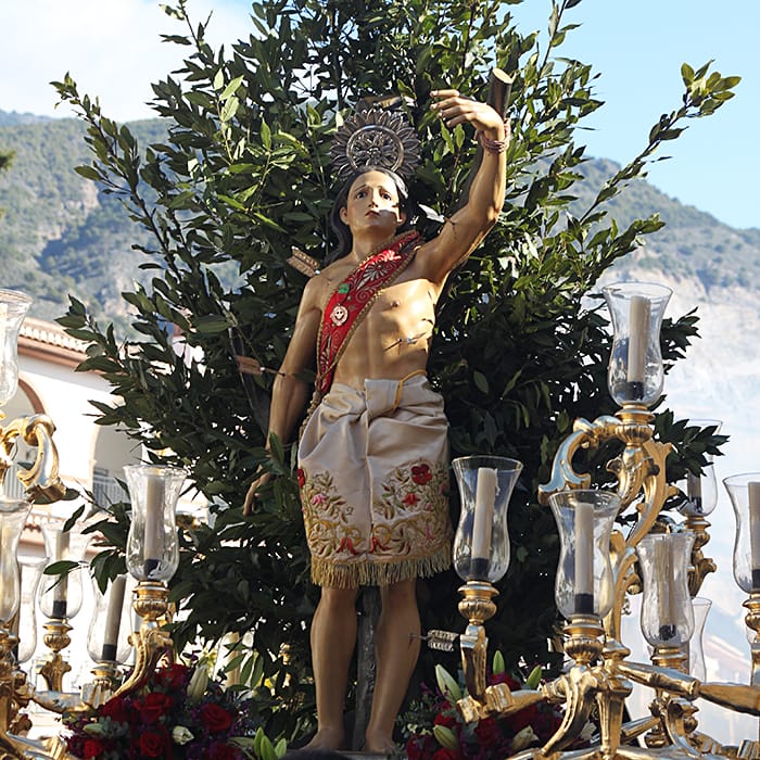 Primer plano de San Sebastián en su paso, entre candelabros y laurel.